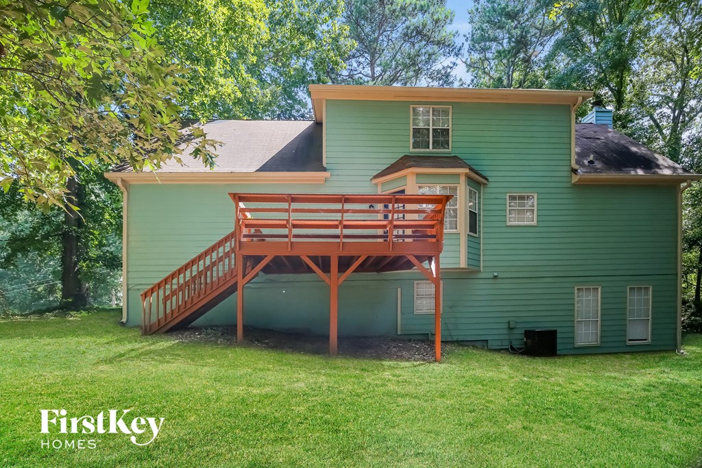 a green house with a wooden deck on the back of it