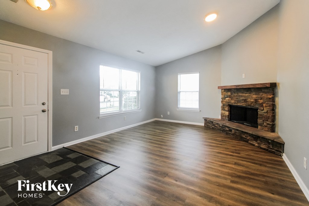 the living room of a house with a fireplace and wooden floors