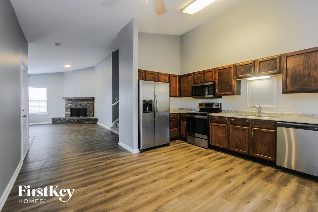 an empty kitchen with wood flooring and stainless steel appliances