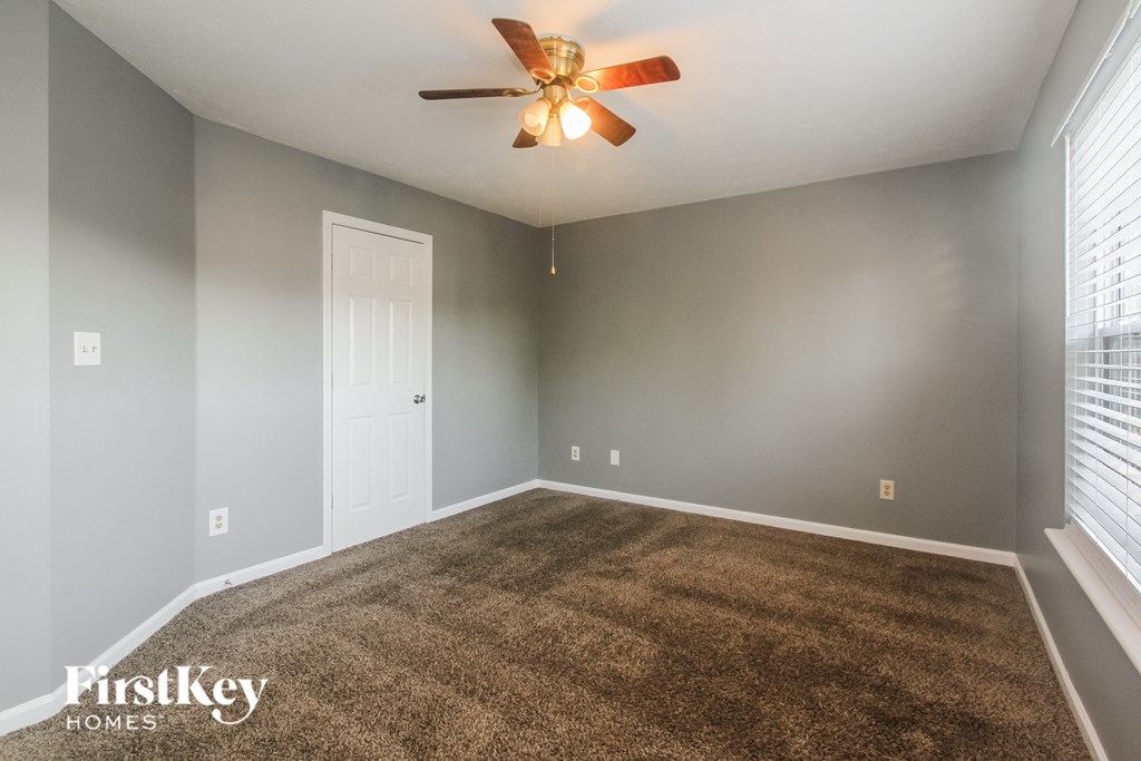 an empty living room with gray walls and a ceiling fan