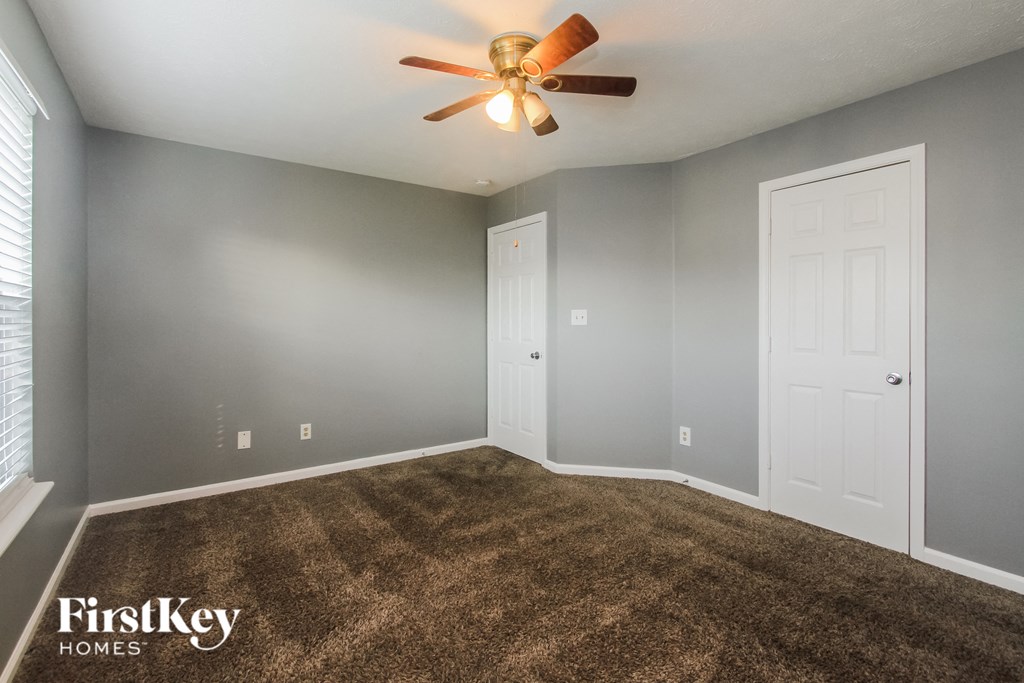 the master bedroom has a carpeted floor and a ceiling fan