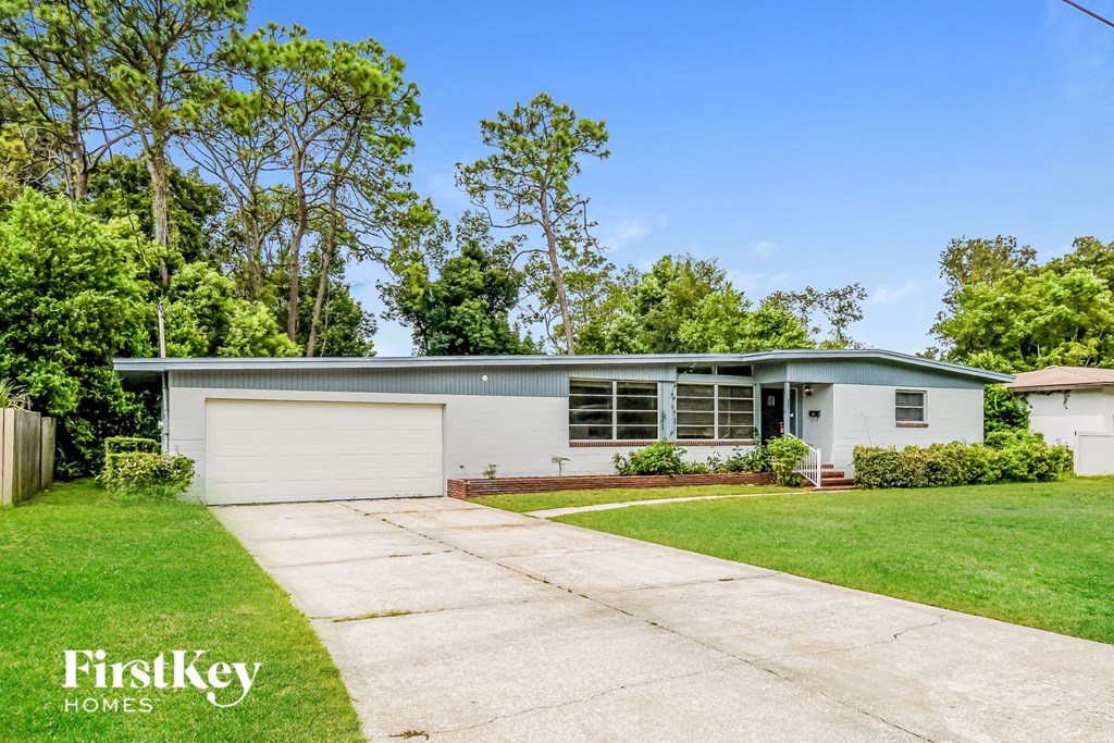 a white and green house with a driveway and lawn