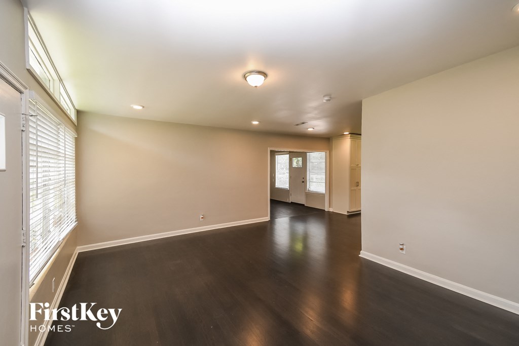 an empty living room with wood floors and white walls