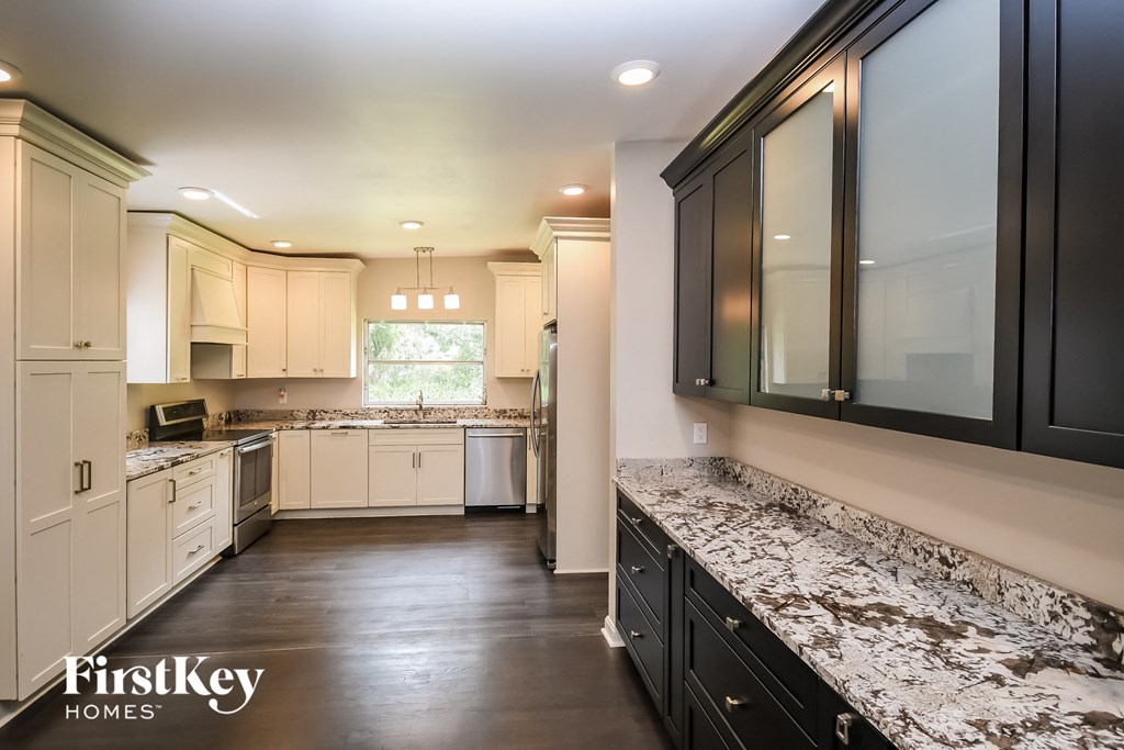 a kitchen with white cabinets and granite counter tops and black cabinets