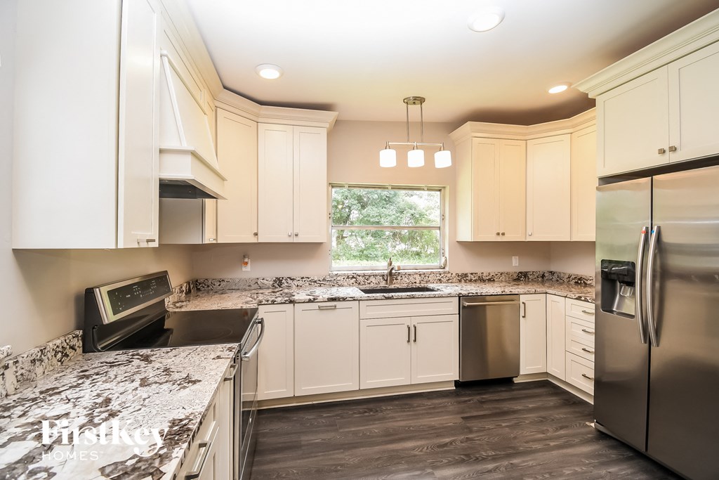 a kitchen with white cabinets and granite counter tops and stainless steel appliances