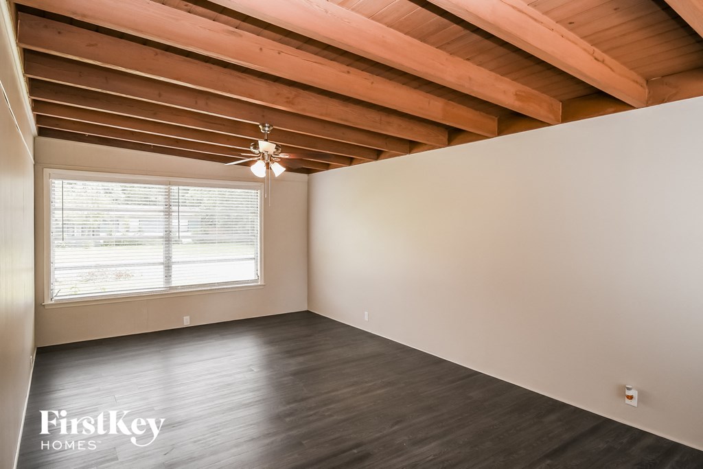 the living room of an empty house with a large window and wood ceilings