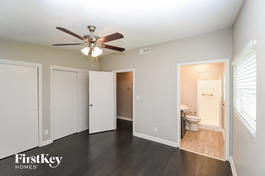 a living room with a ceiling fan and a door to a bathroom