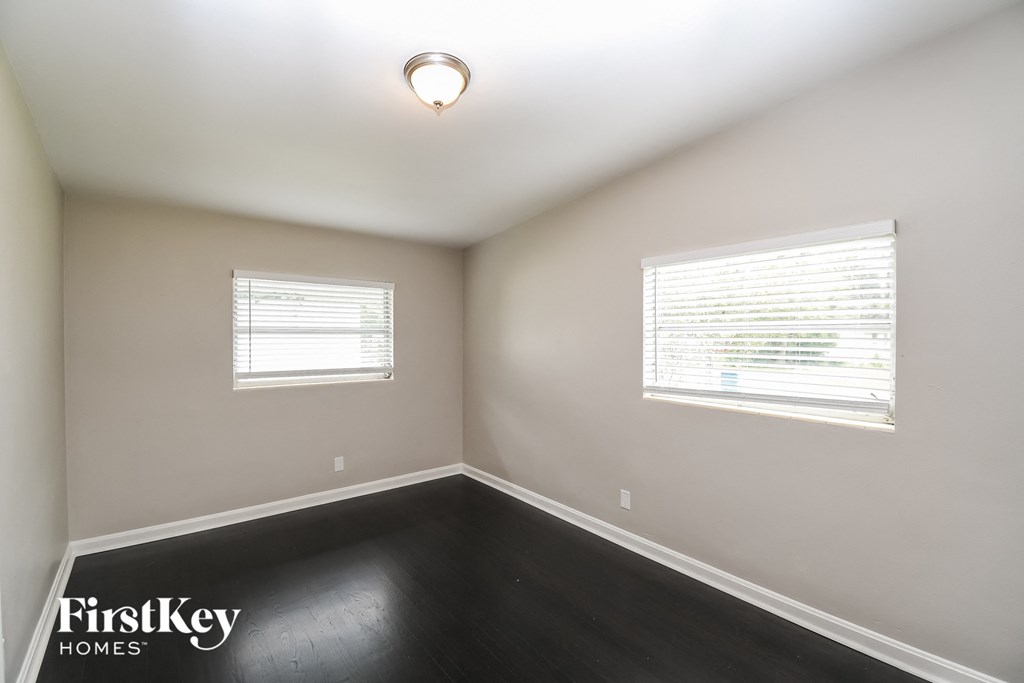 a empty room with two windows and a lamp on the ceiling