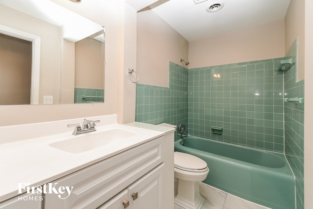 a bathroom with a green tub and a sink and a toilet