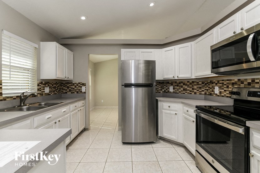 a kitchen with white cabinets and a stainless steel refrigerator