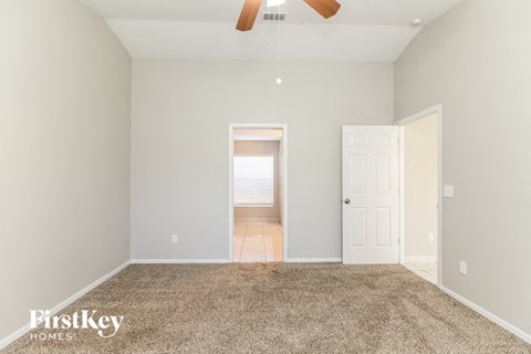 a spacious living room with carpet and a ceiling fan