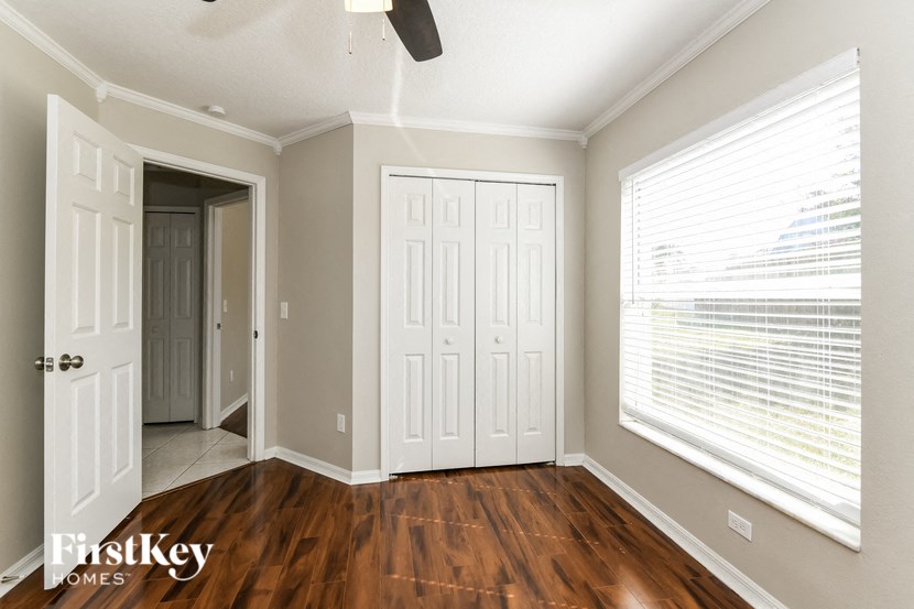 the master bedroom has a large window and hardwood flooring