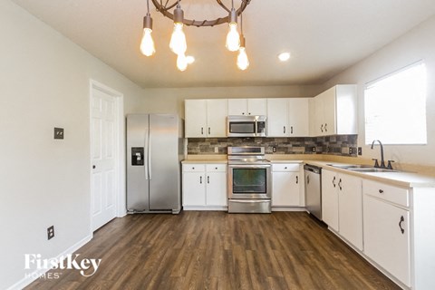 A kitchen with wooden floors and white cabinets.