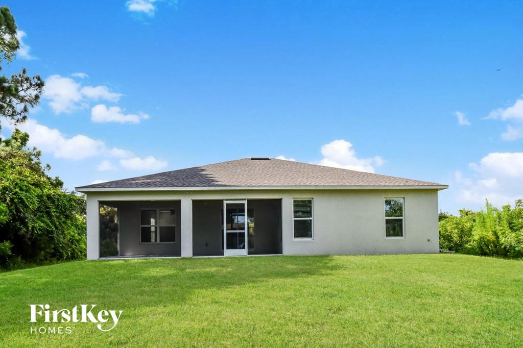 A house with a white exterior and a brown roof is surrounded by green grass.