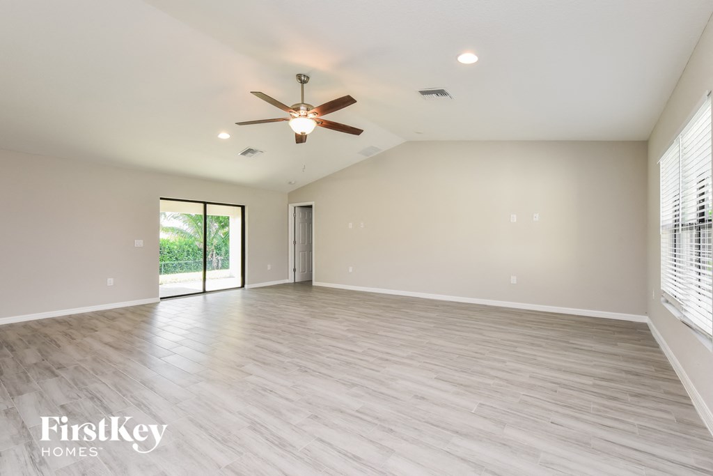 an empty living room with a ceiling fan and a window