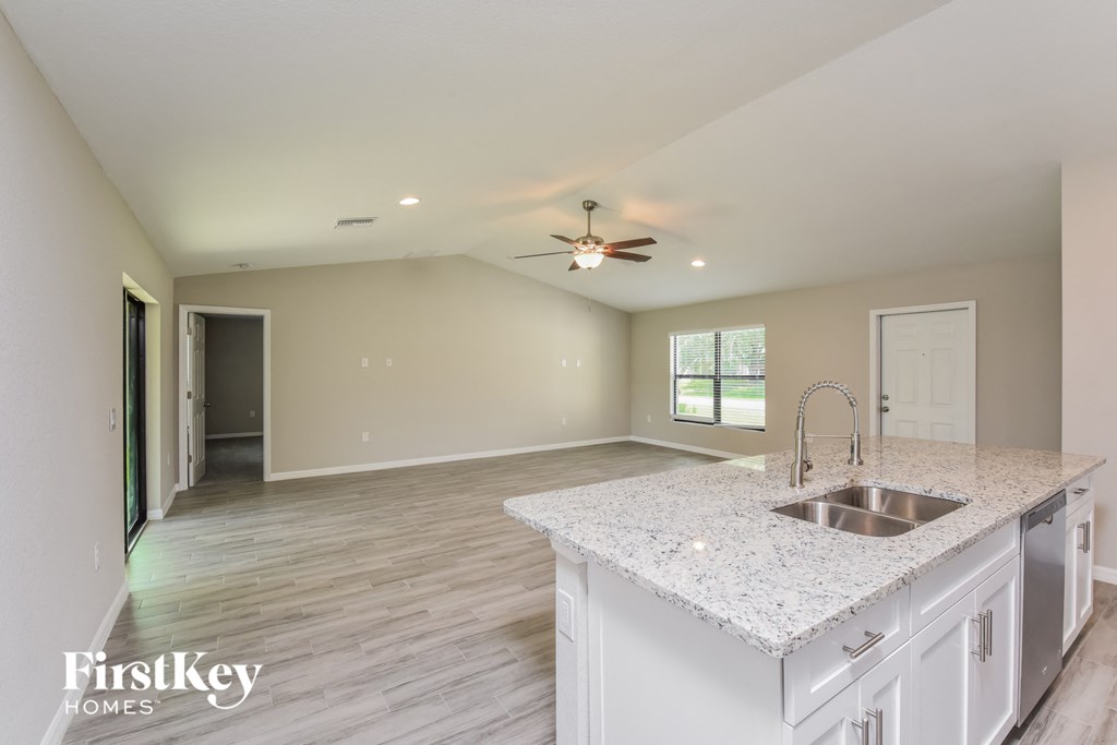 an open kitchen and living room with white cabinets and granite counter tops