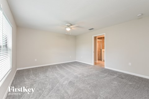 a spacious living room with carpet and a ceiling fan