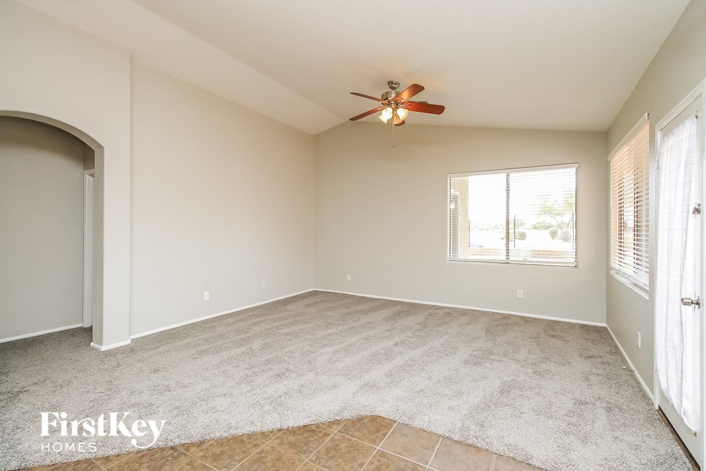 an empty living room with a ceiling fan and a window