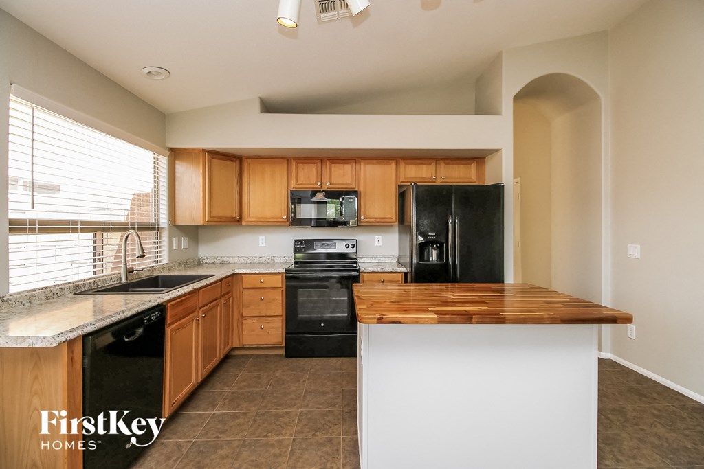 an updated kitchen with black appliances and wood cabinets