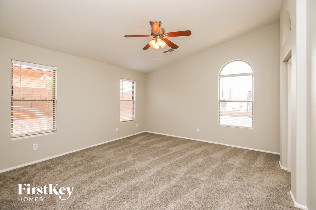a spacious living room with carpet and a ceiling fan