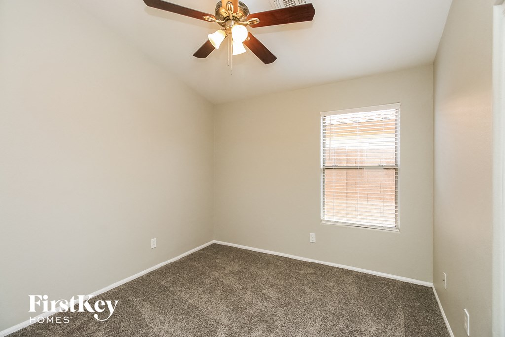 an empty room with a ceiling fan and a window
