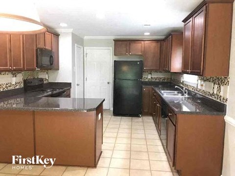 A kitchen with brown cabinets and a black refrigerator.
