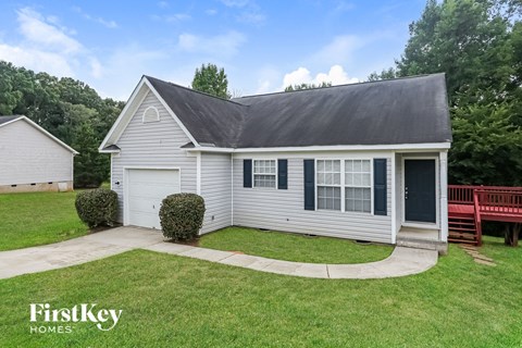 A house with a grey roof and a white garage door is for sale.