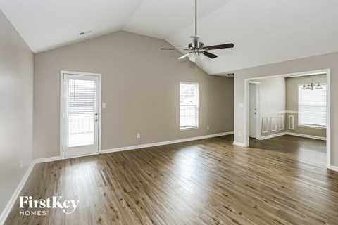 A spacious room with wooden floors and a ceiling fan.