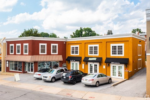 A row of stores with cars parked in front.