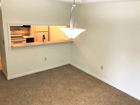 an empty room with a kitchen and a light hanging from the ceiling