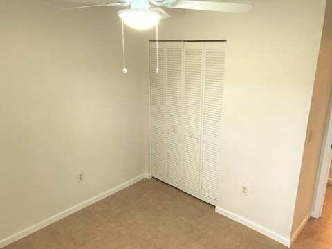 an empty room with a closet and a ceiling fan
