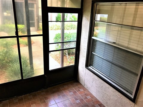 the living room of a house with windows and a brick floor