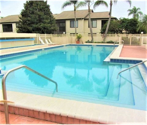 a large swimming pool with a house in the background