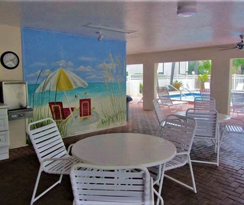 a patio with tables and chairs and a mural on the wall