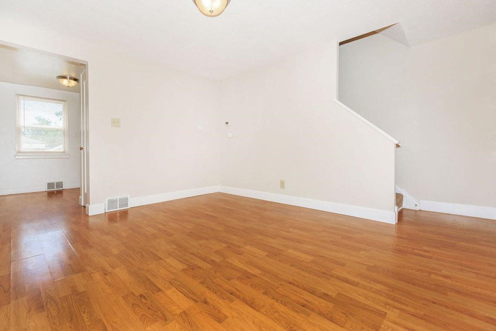 a living room with a hard wood floor and white walls