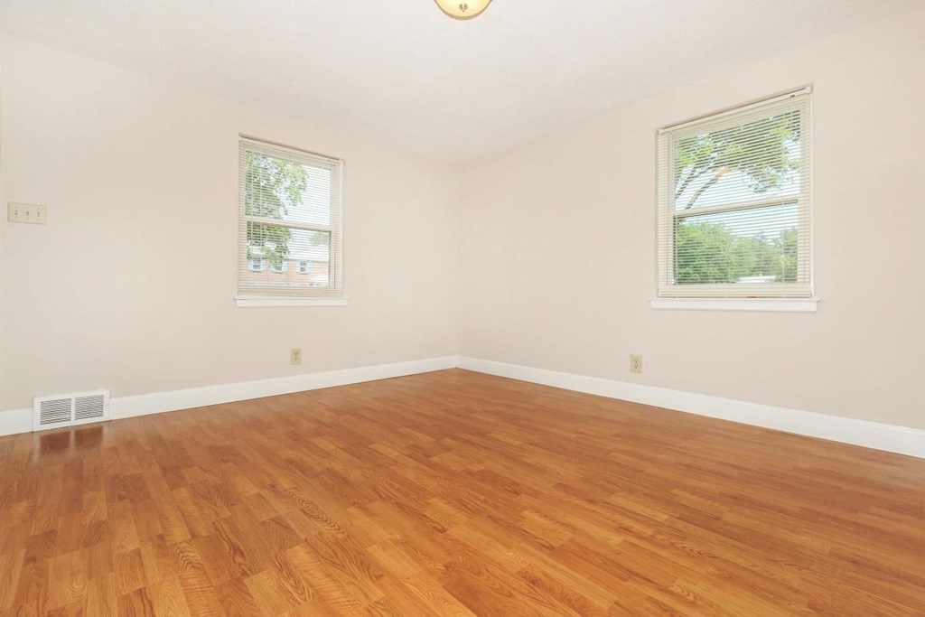 a room with a hard wood floor and two windows