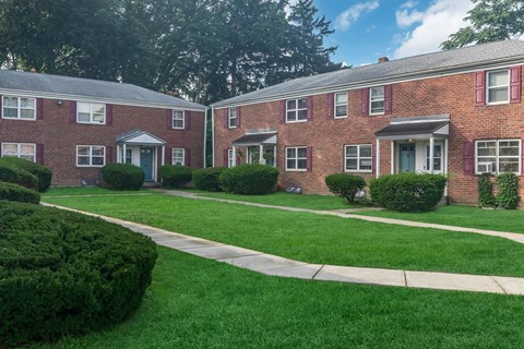 a sidewalk in front of a brick apartment building
