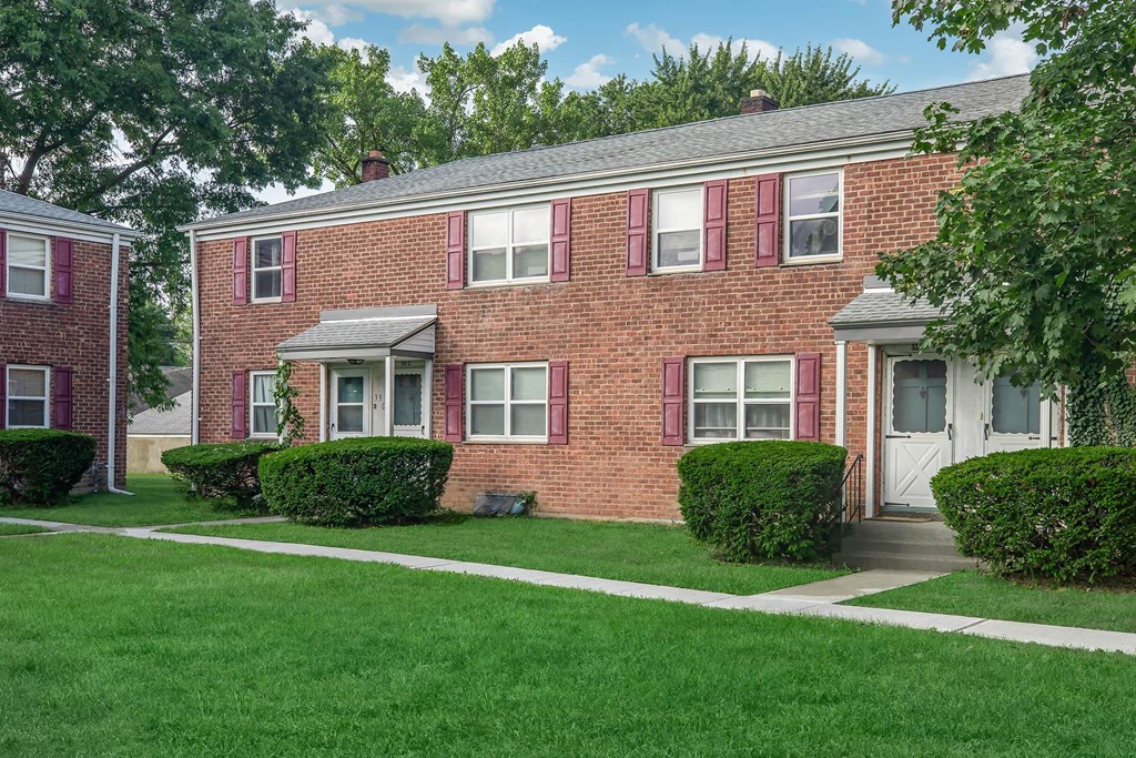 a brick apartment building with a lawn and sidewalk in front of it