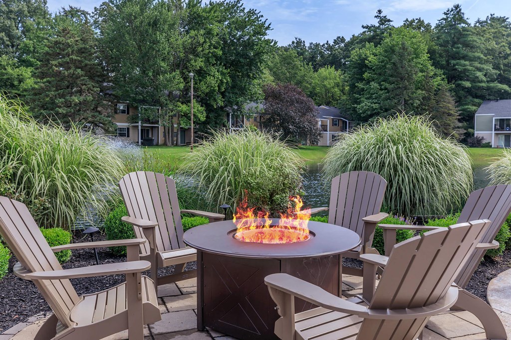 a backyard patio with a fire pit and chairs