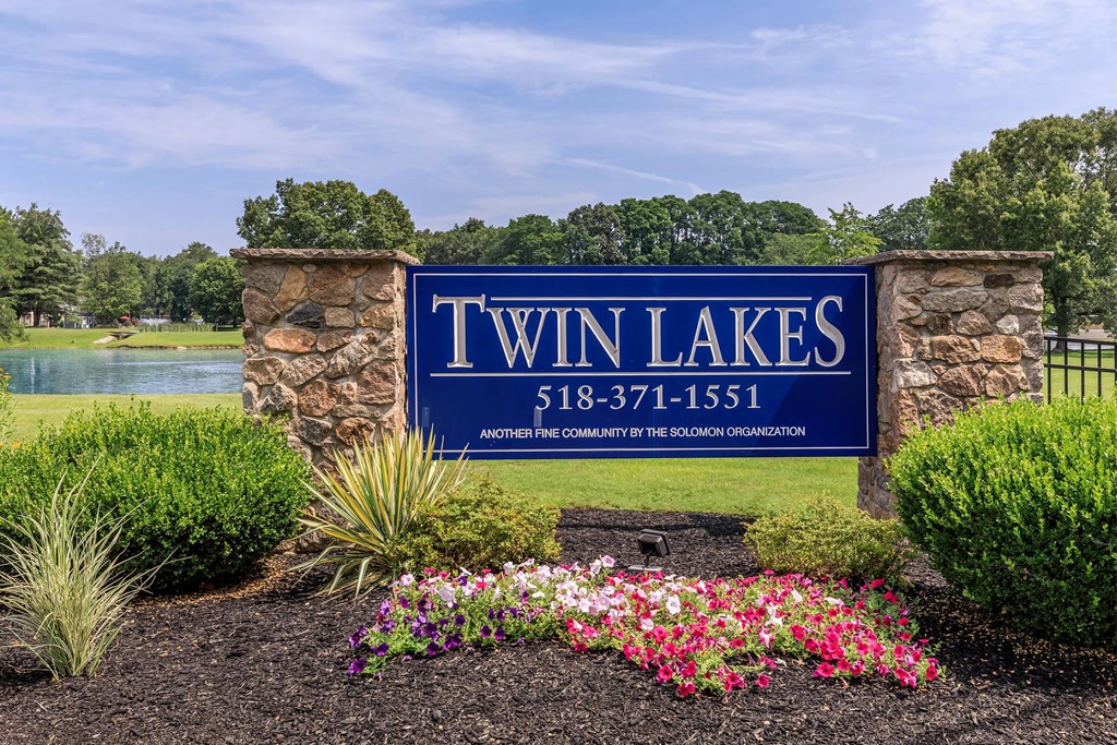 a sign for twin lakes with flowers in front of a lake