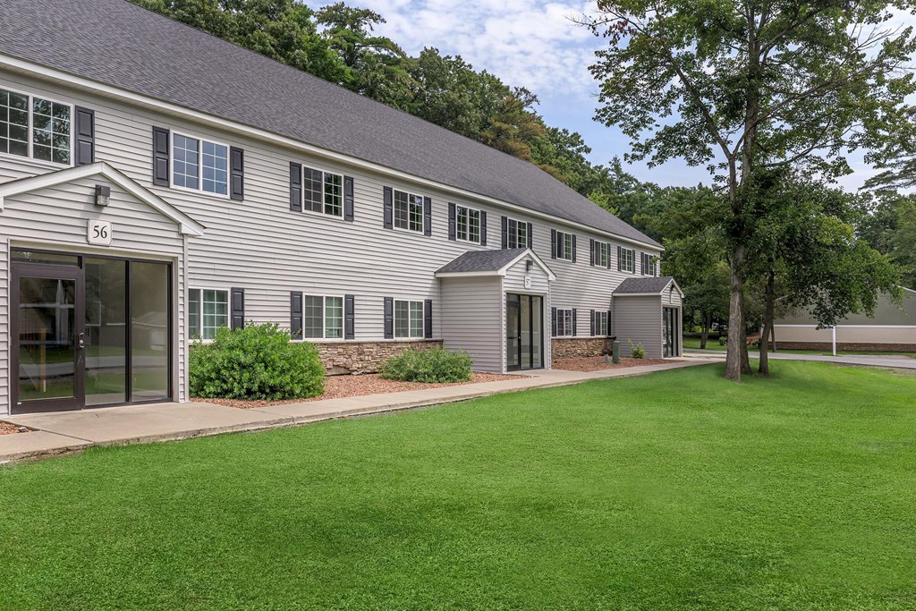 a large white house with a green lawn and trees
