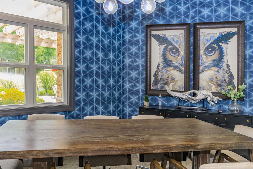 a dining room with a wooden table and chairs and blue wallpaper