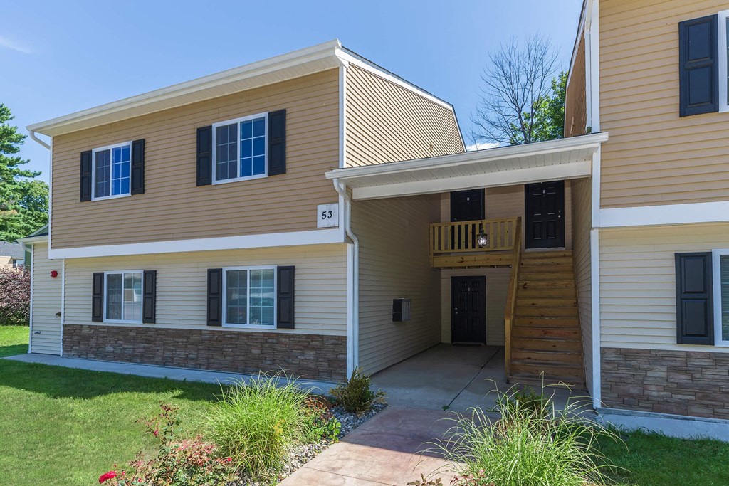 the front of a yellow house with a porch and a walkway