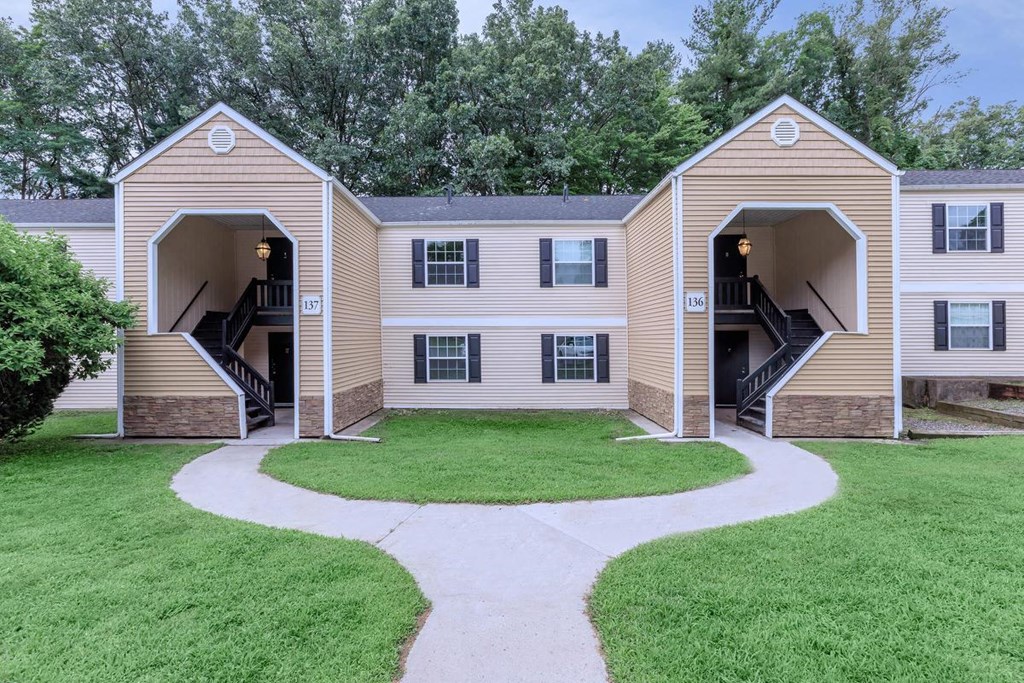 a pathway leading to an apartment building with a yard and stairs