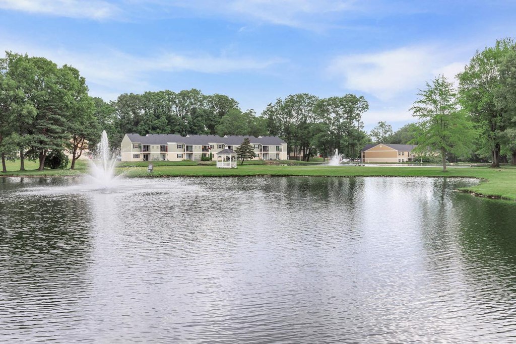 a pond with a fountain in front of a house