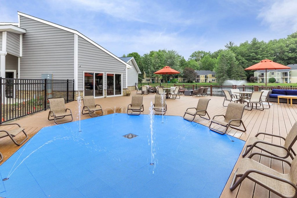 a large pool with chairs and umbrellas and a house