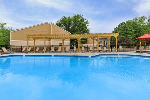 A large swimming pool with a wooden pergola over it.