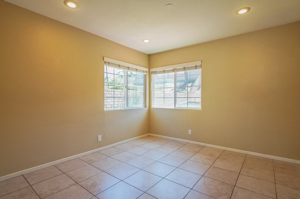 an empty living room with windows and tiled floors