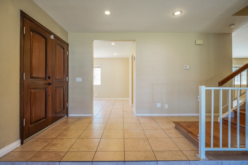 a entryway with a staircase and tiled floors and a wooden door
