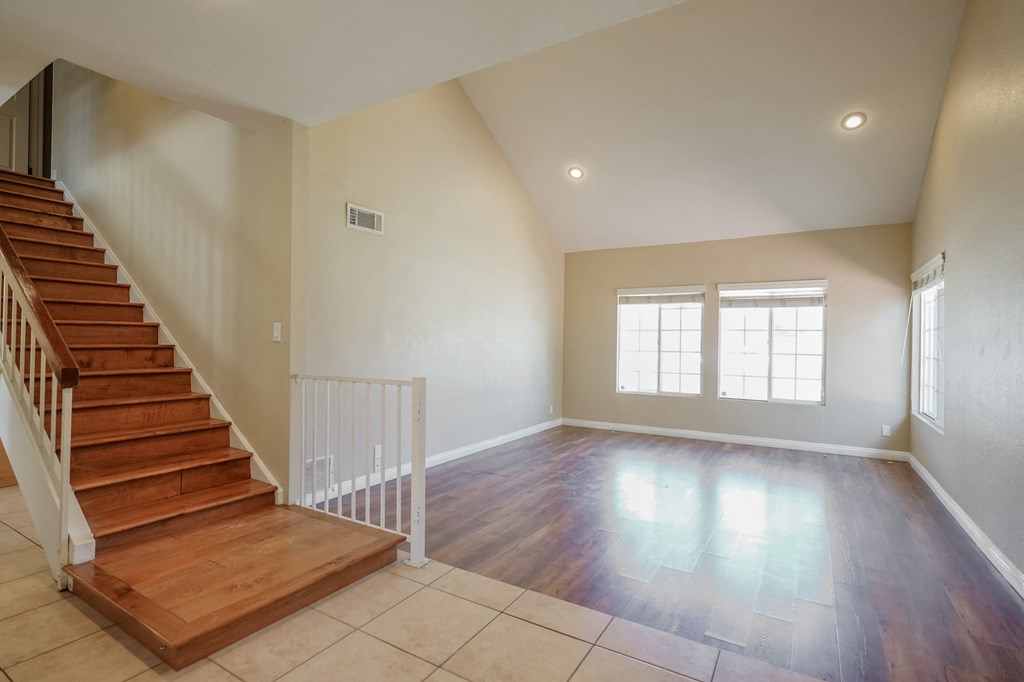 an empty living room with a staircase and a tile floor